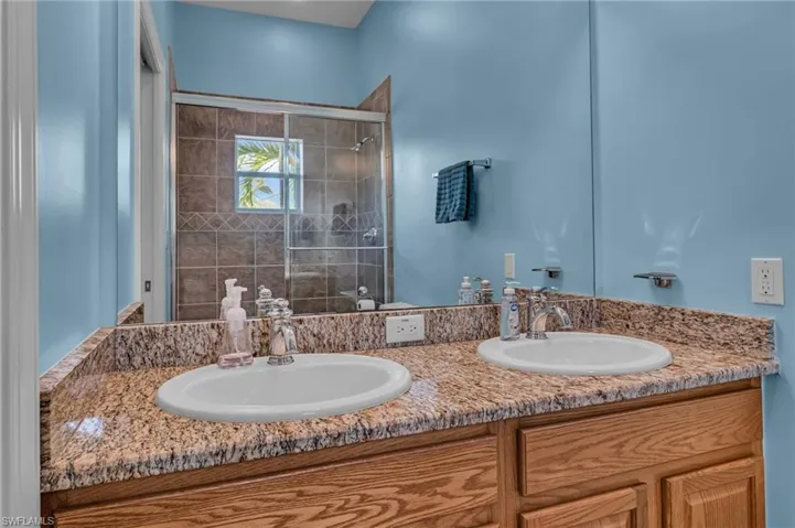 Bathroom with double vanity, a stall shower, and a sink