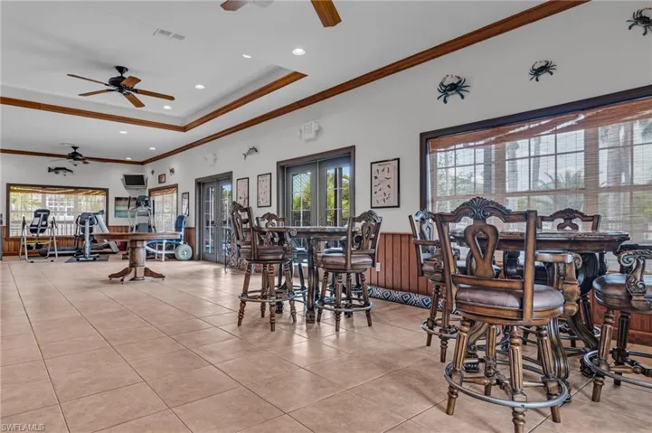 Dining area featuring a dry bar, a tray ceiling, a ceiling fan, and ornamental molding