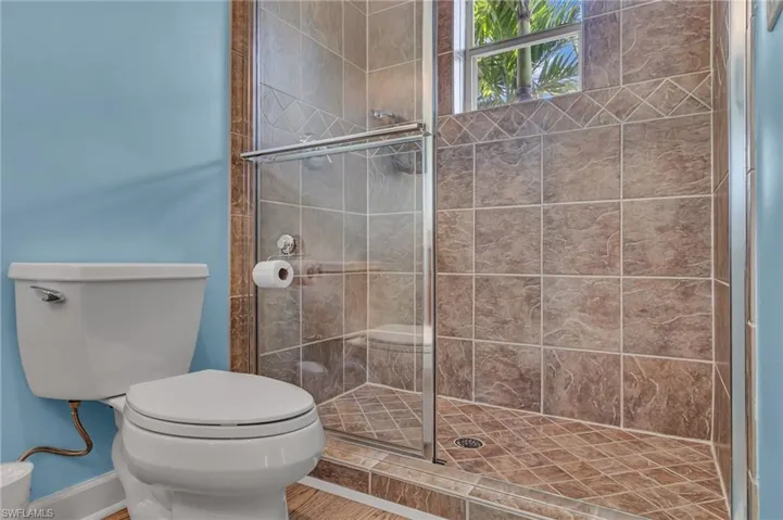 Full bath with a shower stall, toilet, and baseboards