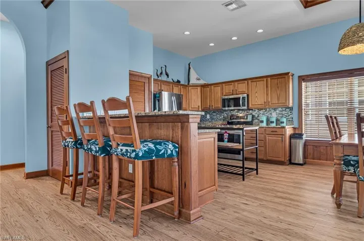 Kitchen featuring light wood-style flooring, visible vents, arched walkways, and appliances with stainless steel finishes