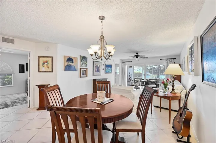 Dining room with a ceiling fan, a chandelier, a textured ceiling, and light tile patterned floors