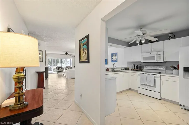 Kitchen featuring ceiling fan, white appliances, light tile patterned floors, light countertops, and a textured ceiling