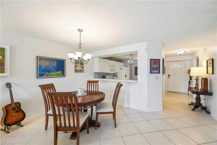 Dining area with ceiling fan, a textured ceiling, a chandelier, and light tile patterned flooring