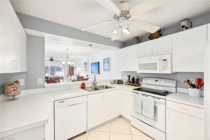 Kitchen featuring ceiling fan, white appliances, light countertops, light tile patterned flooring, and white cabinets