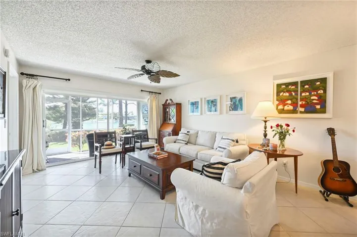 Living room featuring ceiling fan, light tile patterned floors, and a textured ceiling