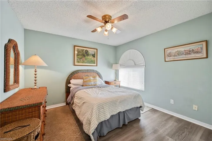 Bedroom with a ceiling fan, wood finished floors, and a textured ceiling