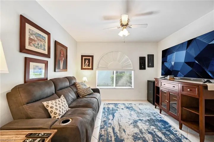 Living room with a ceiling fan and light tile patterned flooring