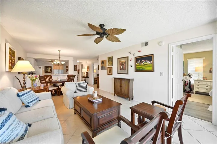 Living room featuring a ceiling fan, a textured ceiling, hanging lights, and light tile patterned floors