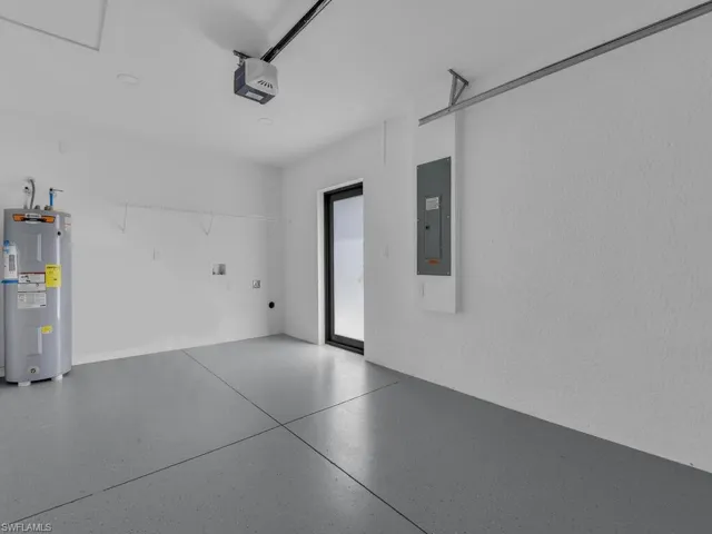 Garage featuring water heater, electric panel, and a garage door opener