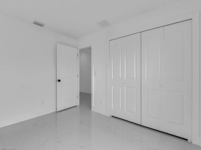 Unfurnished bedroom with light marble finish floors and a closet