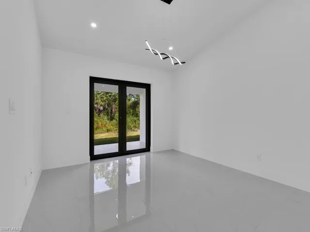 Empty room with light marble finish floors, recessed lighting, and french doors