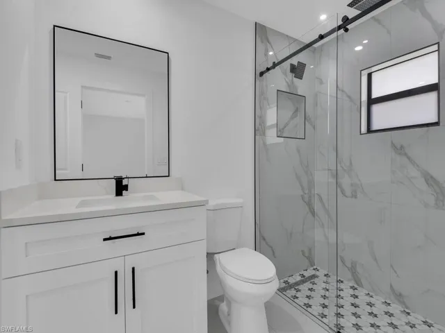 Full bathroom featuring a marble finish shower and vanity