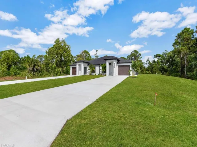 Prairie-style house with a garage, a front lawn, driveway, and view of scattered trees