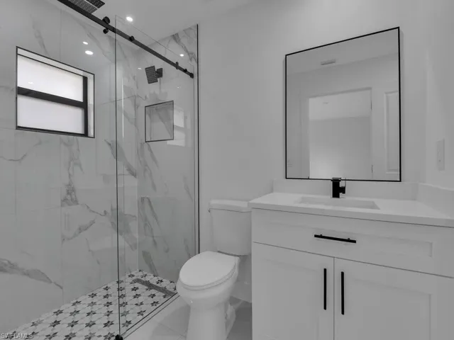 Full bath featuring a marble finish shower, vanity, and tile patterned flooring