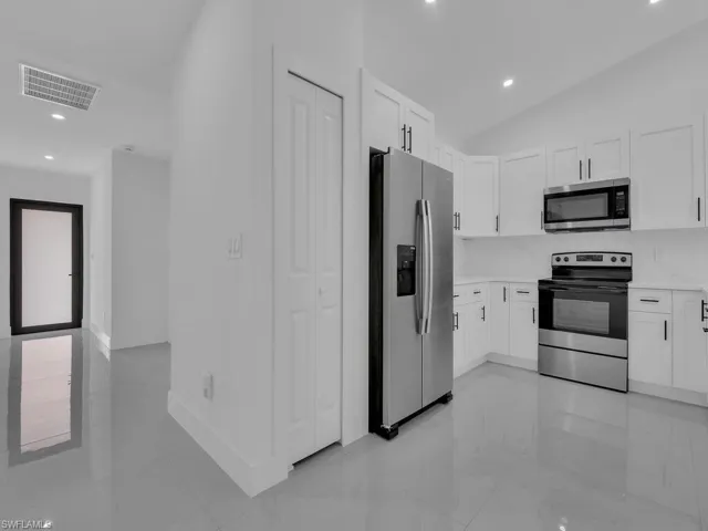 Kitchen with appliances with stainless steel finishes, white cabinetry, recessed lighting, vaulted ceiling, and backsplash