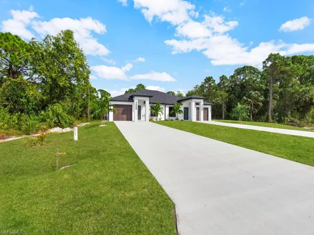Prairie-style home with a front lawn, an attached garage, and concrete driveway