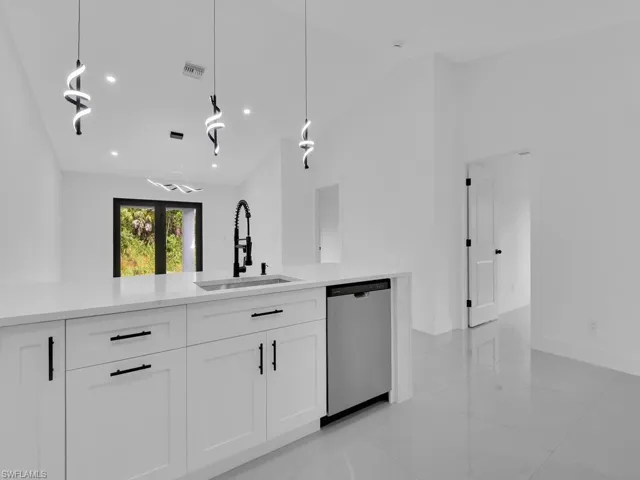 Kitchen featuring white cabinets, dishwasher, decorative light fixtures, light stone counters, and recessed lighting