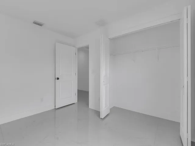 Unfurnished bedroom with light marble finish floors and a closet