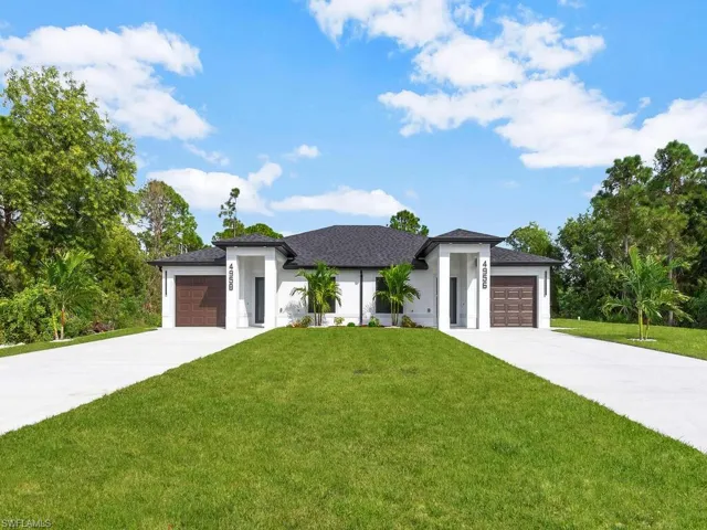Prairie-style house with a front yard, stucco siding, a garage, and concrete driveway