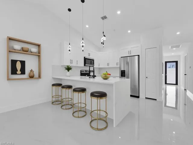 Kitchen featuring a breakfast bar, pendant lighting, white cabinets, stainless steel appliances, and a peninsula