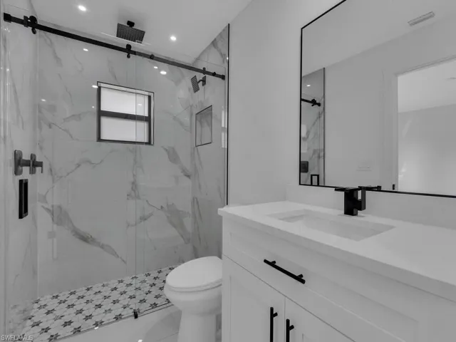 Bathroom with vanity and a marble finish shower