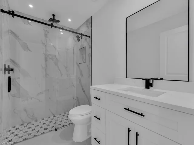 Bathroom featuring vanity and a marble finish shower
