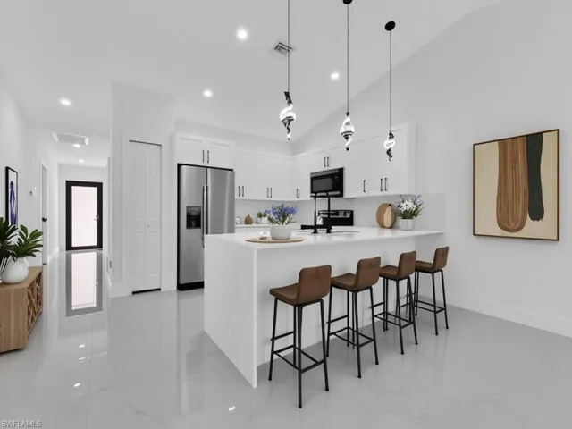 Kitchen with a breakfast bar area, decorative light fixtures, white cabinets, a peninsula, and stainless steel refrigerator with ice dispenser