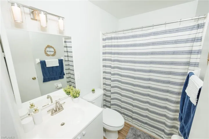 Bathroom featuring hardwood / wood-style floors, vanity, toilet, and walk in shower
