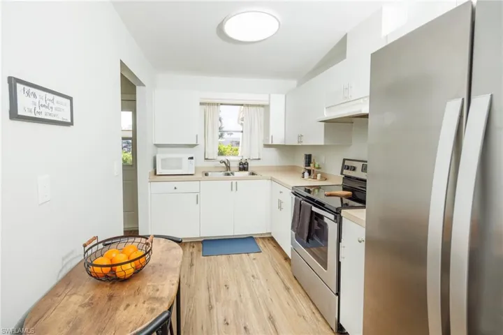 Kitchen featuring light wood-type flooring, stainless steel appliances, white cabinetry, and sink