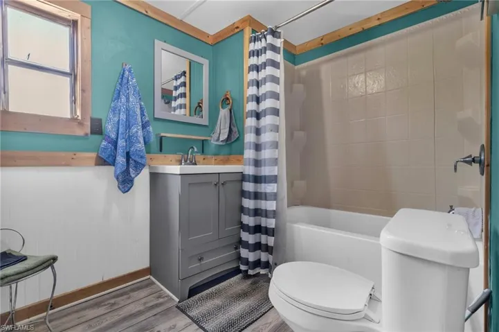 Full bath featuring wood finished floors, shower / tub combo, toilet, and vanity