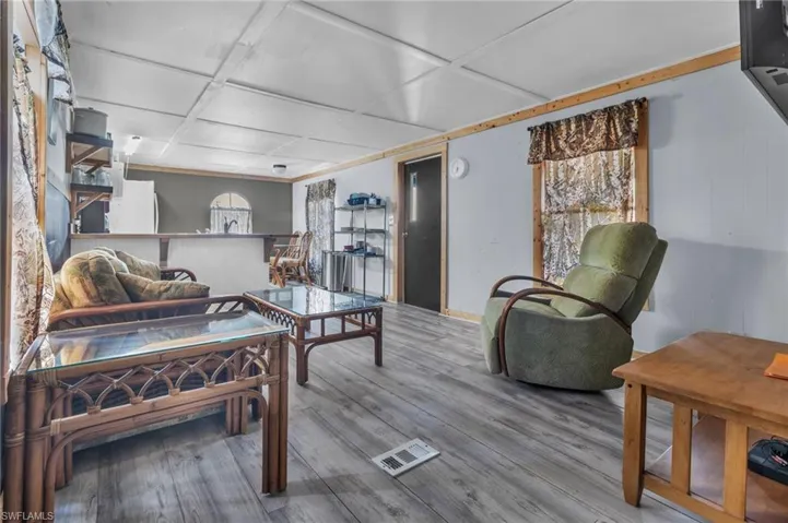 Living room featuring visible vents, wood finished floors, coffered ceiling, and a healthy amount of sunlight