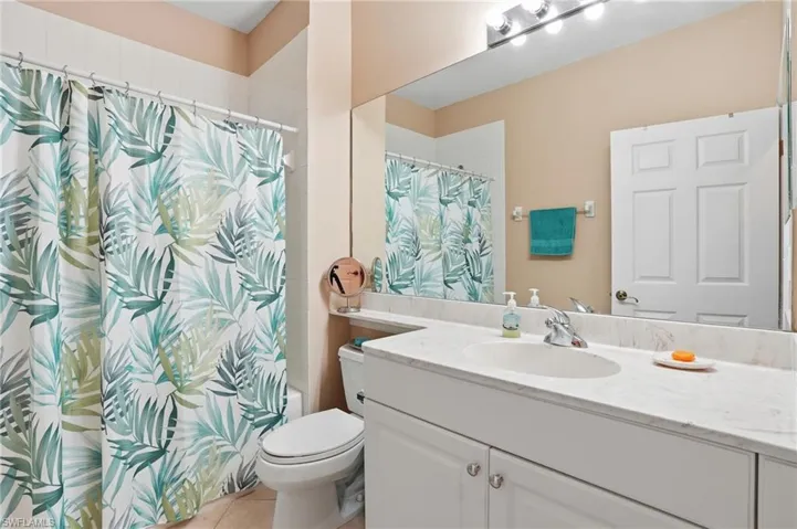 Full bath featuring vanity, shower / bathtub combination with curtain, and light tile patterned floors