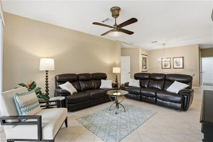 Living room with light tile patterned floors, a ceiling fan, and hanging lights
