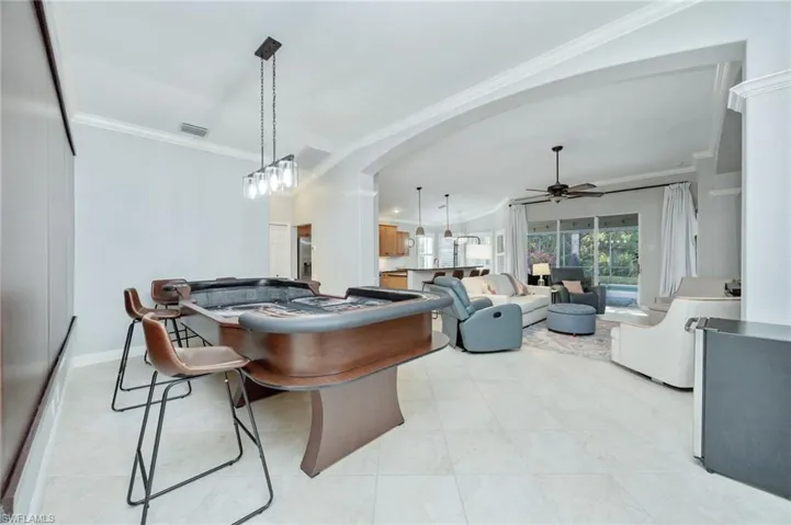 Dining area with a ceiling fan, ornamental molding, lofted ceiling, arched walkways, and light tile patterned floors