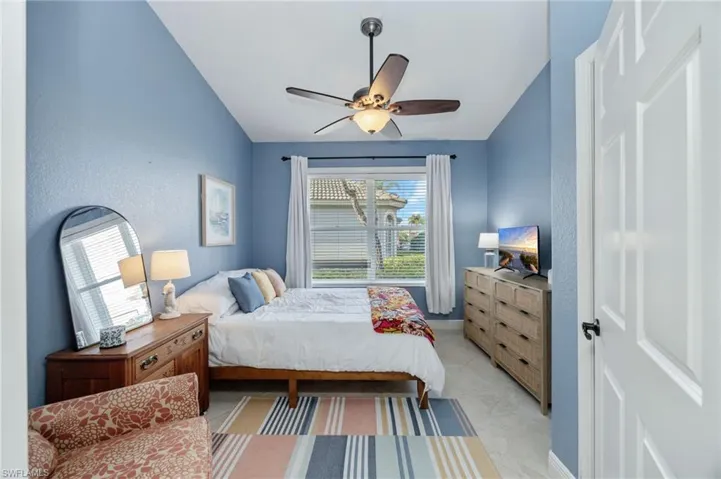 Bedroom with vaulted ceiling, ceiling fan, and a textured wall