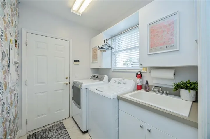 Laundry room with cabinet space, washer and dryer, and light tile patterned floors