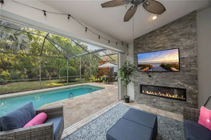 Swimming pool featuring a patio, a sunroom, glass enclosure, and an outdoor living space with a fireplace