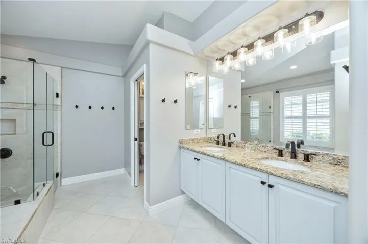 Bathroom with double vanity, a stall shower, and light tile patterned floors