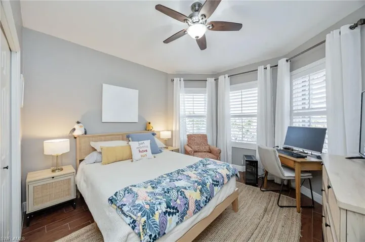 Bedroom with dark wood-style flooring, a ceiling fan, and a desk