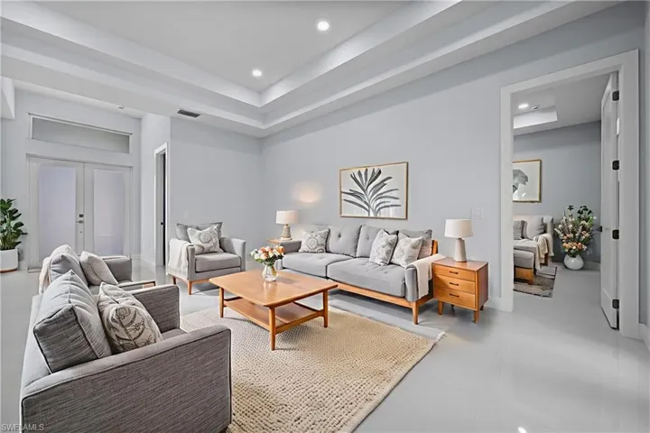 Living room with a tray ceiling, french doors, and recessed lighting