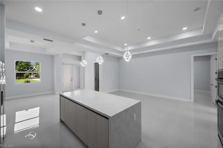 Kitchen with a tray ceiling, modern cabinets, a center island, open floor plan, and recessed lighting