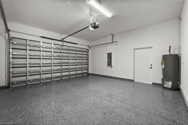 Garage featuring water heater, a garage door opener, and electric panel