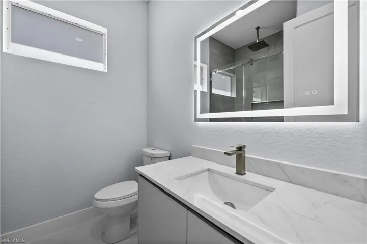 Full bath featuring vanity, a textured wall, and a walk in shower