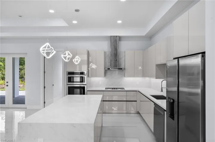 Kitchen with stainless steel appliances, modern cabinets, decorative backsplash, recessed lighting, and wall chimney range hood
