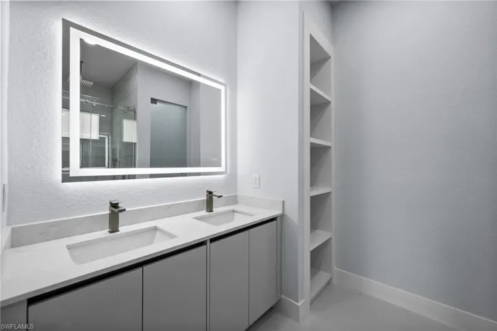 Full bathroom with a textured wall, a stall shower, and double vanity