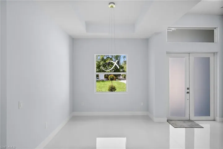 Unfurnished dining area with light tile patterned floors and a tray ceiling
