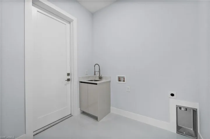 Washroom featuring electric dryer hookup, washer hookup, cabinet space, and light tile patterned floors