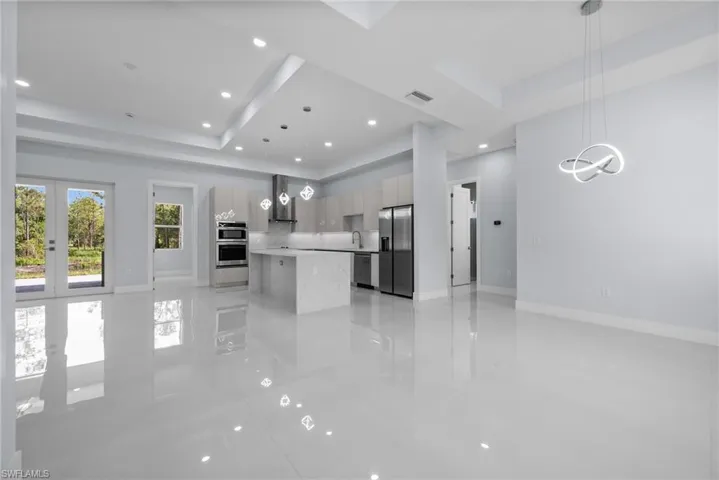 Kitchen featuring modern cabinets, stainless steel appliances, a raised ceiling, extractor fan, and light countertops
