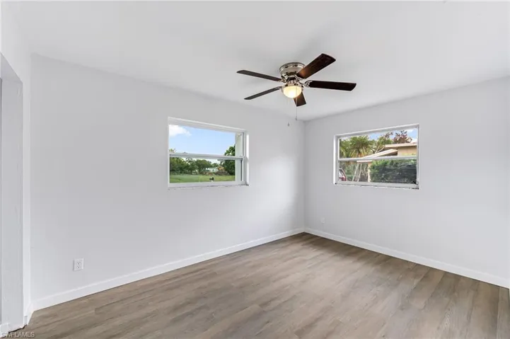 Unfurnished room featuring ceiling fan, a wealth of natural light, and hardwood / wood-style floors
