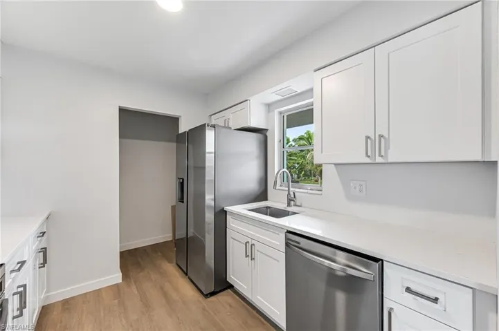 Kitchen featuring appliances with stainless steel finishes, white cabinets, sink, and light hardwood / wood-style floors